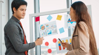 İş adamları ofisteki proje planlama kurulunda çalışıyor ve proje gelişimini analiz etmek için iş arkadaşlarıyla sohbet ediyorlar. Düzenli olması için cama yapıştırılmış yapışkan notlar kullanıyorlar. Jivy