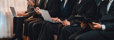 Asyalı iş başvurusu için başvuran kişi iş görüşmesi için bekleme odasında oturuyor. Ofis çalışanı ya da iş adamları dizüstü bilgisayar ve telefon kullanarak sıkışık bir odada birlikte çalışıyorlar. Önde.
