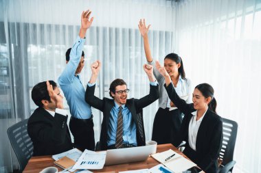 Kutlama jesti ve başarılı takım çalışması yapan bir grup mutlu iş adamı. Çeşitli yarış bürosu çalışanları şirket ofisinde pazarlama planlamasında ilerleme kaydettikten sonra kutlama yapıyorlar. Habiliment