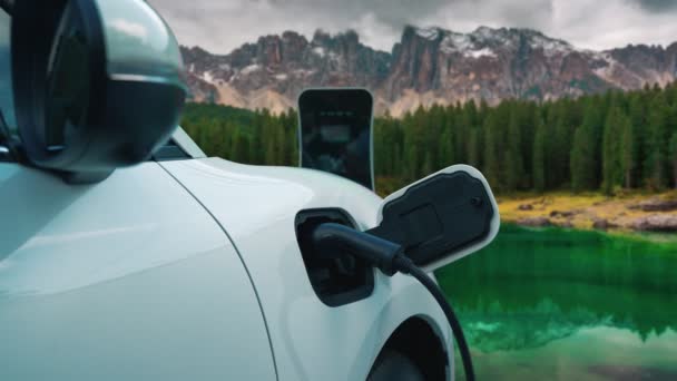 クリーンな環境のためのクリーンエネルギーによって駆動電気自動車の進歩的な概念の背景として山の上の空に雲の時間経過と自然景観 充電ステーションでのEv車の充電 — ストック動画