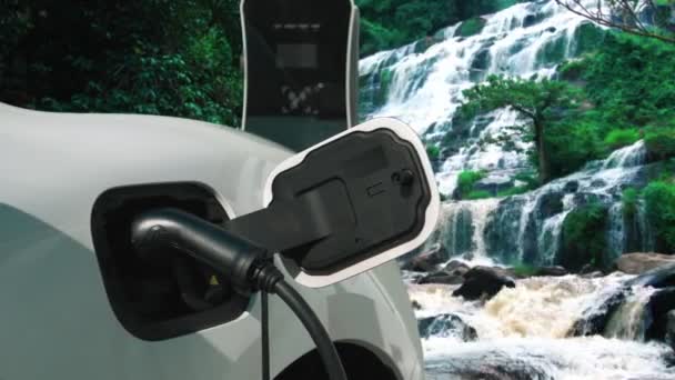 自然景観 滝やストリームの背景に充電ステーションから電気自動車の充電エネルギー 再生可能エネルギーを動力とするEv車によるエネルギー持続可能性の進歩的な概念 — ストック動画