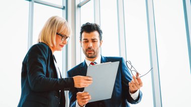 İki iş adamı toplantı odasında proje stratejisi hakkında konuşuyor. İş adamı, iş yerinde iş arkadaşlarıyla proje planlamasını tartışırken aynı zamanda mali raporla ilgili sohbet ve tavsiyelerde bulunuyor. Jivy