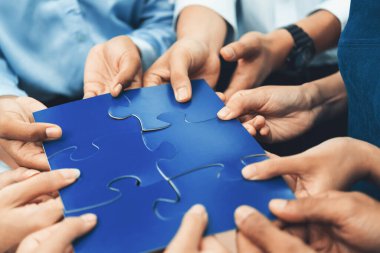 Çeşitli şirket çalışanları, ortaklık ve takım çalışmasını temsil etmek için bulmaca parçalarını birleştirerek ofiste işbirliği yapıyor. Yapboz 'u birleştirerek iş dünyasındaki birlik ve sinerji. Uyum