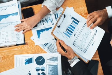 Üst düzey iş analist grubu toplantı masasındaki finansal veri raporunu analiz ediyor. İş zekası analizine göre çizelge ve grafik paneli. Çok titiz.