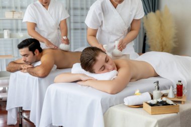 Sıcak bitkisel top spa masaj vücut tedavisi, masör nazikçe bitki torbasını çift müşteri vücuduna bastırıyor. Aromaterapi dinlenme sükuneti ve sükuneti kaplıca salonundaki atmosferi aydınlatıyor. Sessiz.