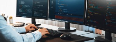 Bilgisayar ekranında uygulama geliştirme üzerine çalışan yazılım mühendisi. Teknoloji şirketinin işyerindeki monitörde betik ve kod. Uygulama geliştirici kod çözme ve yazma. Önde.