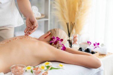 Lüks spa salonlarında sıcak mum ışığında cilt bakımı yaptıran kadın müşteri. Sağlık Spa vücut fırçasında tuz temizleme güzellik tedavisi. Sessiz.