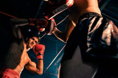 Asyalı ve Kafkasyalı Muay Thai boksörü boks antrenmanında boks antrenmanında boks antrenörüne yumruk atma, Muay Thai boks tekniği ve becerilerini sergileme. Impetus