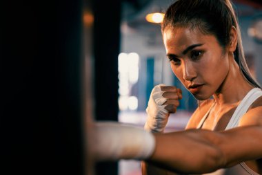 Asyalı kadın Muya Thai boksör eğitimi, spor salonunda kum torbasına yumruk atma. Sağlıklı spor ve spor yaşam tarzı, boks maçı için güç ve dayanıklılık eğitimi. Impetus