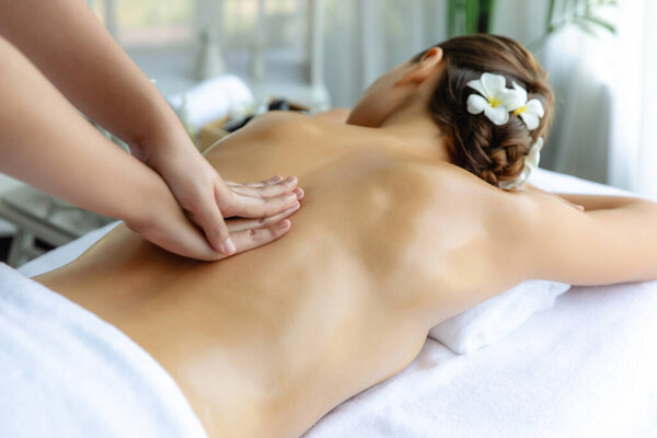 Caucasian woman customer enjoying relaxing anti-stress spa massage and pampering with beauty skin recreation leisure in day light ambient salon spa at luxury resort or hotel. Quiescent