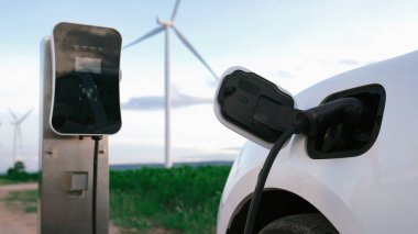 Çevreyi korumak için rüzgar türbininden yeşil ve yenilenebilir enerjiyle çalışan şarj istasyonunda şarj edilen gelişmiş gelecek enerji altyapısı konsepti.