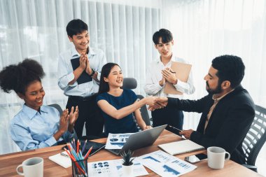 Çeşitli iş arkadaşları başarıyı şirket işyerindeki el sıkışma ve takım çalışmasıyla kutluyor. Çok kültürlü, mutlu profesyonellerden oluşan bir ekip ofiste tokalaşarak birlik oldular. Uyum