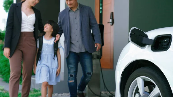 電気自動車と家庭用充電ステーションを備えた進歩的な若い両親と娘 健康的な環境のための電気自動車からの緑ときれいなエネルギー 再生可能エネルギーからのエコパワー — ストック写真