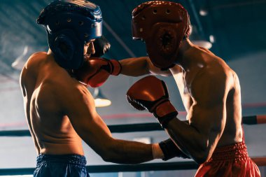 Kasklı iki atletik ve kaslı vücut boksörü ya da boks baş muhafızı vahşi bir boks maçında karşı karşıya. Boks dövüşçüsü boks ringinde dövüşüyor. Impetus
