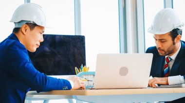 Mühendis ve mimar, mühendislik ve mimari proje planlaması hakkında ofis masasında toplanıyorlar. Jivy