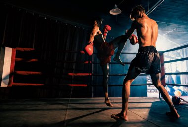 Asyalı ve Kafkasyalı Muay Thai boksörü boks antrenmanında diz atağı yapıyor, antrenörlerine diz vuruşu yapıyor, Muay Thai boks tekniği ve becerilerini sergiliyor. Impetus