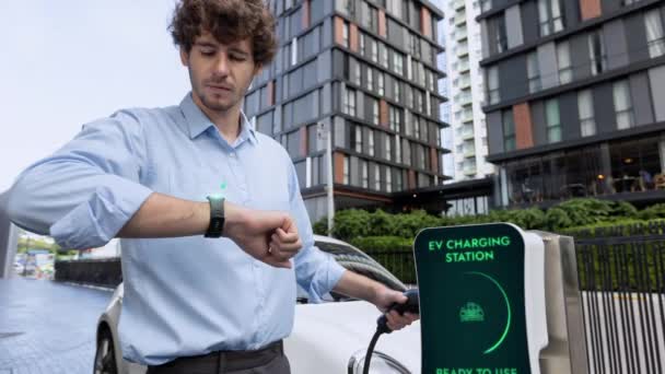 Empresário Verificando Estado Bateria Carro Holograma Smartwactch Durante Recarga Estação — Vídeo de Stock