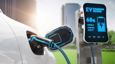 EV şarj kablosu ile elektrik yüklemek için elektrik istasyonuna eko yeşil şehir parkındaki elektrik kablosu takıldı. Geleceğin yenilikçi EV arabası alternatif temiz enerji kullanarak CO2 'yi azaltıyor. İnceleyin