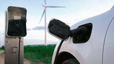 Çevreyi korumak için rüzgar türbininden yeşil ve yenilenebilir enerjiyle çalışan şarj istasyonunda şarj edilen gelişmiş gelecek enerji altyapısı konsepti.