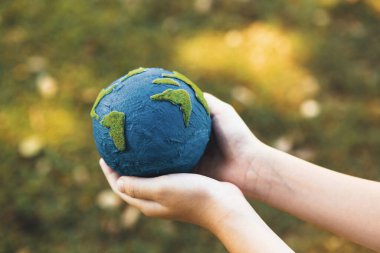 Dünya gezegenini ESG ilkesi ve çevre dostu enerjisiyle daha parlak bir gelecek için Dünya günü olarak el ele tutuşan genç çocuklar. Döngü