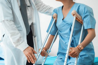 Doktor hastanede koltuk değnekli hastayla ilgileniyor. Fizyoterapist ve bacak yaralanması konsepti. Jivy