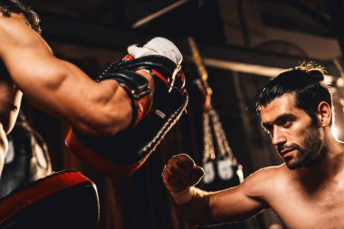 Asyalı ve Kafkasyalı Muay Thai boksörü boks antrenmanında boks antrenmanında boks antrenörüne yumruk atma, Muay Thai boks tekniği ve becerilerini sergileme. Impetus