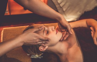 Beyaz kadın stres önleyici kafa masajı yapmaktan ve lüks otel veya otelde sıcak mum ışığında yüz güzelliği eğlencesi yapmaktan zevk alıyor. Sessiz.