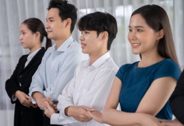 Mutlu ve gülümseyen çok ırklı ofis çalışanı, sinerjiyi ve ticari başarı için işbirliğini destekleyen bir kuyrukta el ele tutuşuyor. Modern işyerinde çeşitli profesyonel ofis çalışanları arasında bağ var. Uyum