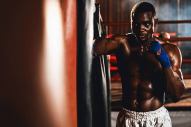 Afrika kökenli siyah boksör boks çantasına tekme atıyor. Spor salonunda boks torbası eğitim ekipmanı olarak. Profesyonel boks maçı için dayanıklılık ve dayanıklılık için. Impetus