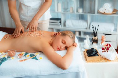 Lüks spa salonlarında sıcak mum ışığında cilt bakımı yaptıran kadın müşteri. Sağlık Spa vücut fırçasında tuz temizleme güzellik tedavisi. Sessiz.