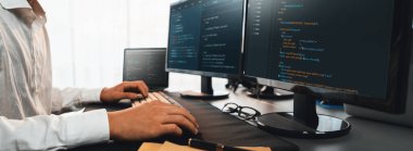 Bilgisayar ekranında uygulama geliştirme üzerine çalışan yazılım mühendisi. Teknoloji şirketinin işyerindeki monitörde betik ve kod. Uygulama geliştirici kod çözme ve yazma. Önde.