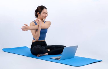 İnternetteki videodan alınan talimatlara göre spor kıyafeti giymiş genç Asyalı bir kadın spor egzersizinden önce geriniyor. Sağlıklı atletik bir kadınla vücut egzersizi izole bir zeminde ısınıyor. Kuvvetli