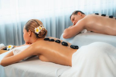 Lüks tatil köyündeki kaplıca salonunda sıcak taş masajı. Gündüz dinginliği ortam, mutlu çift müşterileri bazalt taşı masajının keyfini çıkarıyor. Rahatlatıcı bir sıcaklıkla vücudun üzerinde süzülüyorlar. Sessiz.