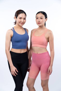 Spor kıyafetli iki Asyalı kadın vücut portresi, gülümsüyor ve neşeli bir jest yapıyorlar. Çekici bir kızla egzersiz yapmak sağlıklı yaşam tarzını sürdürmeye yöneliktir. İzole edilmiş arka plan Vigorous