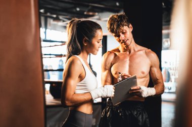 Asyalı bayan Muay Thai boksörü ve kişisel boks antrenörü spor salonundaki fiziksel ilerlemesini tartışıyor. Vücut kası gelişimine ve boks performansına bağlılığını yansıtıyor. Impetus