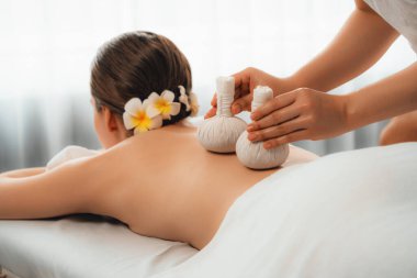 Sıcak bitkisel top spa masaj vücut tedavisi, masör nazikçe bitki torbasını çift müşteri vücuduna bastırıyor. Aromaterapi dinlenme sükuneti ve sükuneti kaplıca salonundaki atmosferi aydınlatıyor. Sessiz.