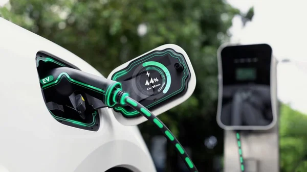 电动汽车插头从充电站插入电动汽车充电器电缆 在生态绿地和树叶背景下显示智能数字电池状态全息图 能源可持续发展技术进步 — 图库照片