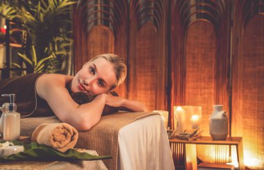 Beyaz kadın müşteri stres önleyici spa masajının keyfini çıkarıyor ve lüks otel ya da otelde sıcak mum ışığında güzellik teniyle eğleniyor. Sessiz.