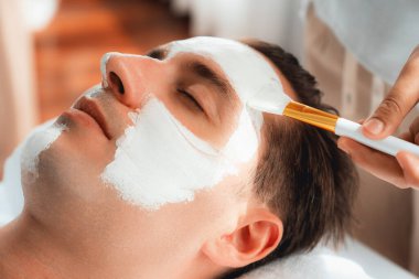 Kaplıca salonunun sakin atmosferi, insan müşterisi modern gün ışığında lüks yüz kremi masajıyla kendini yenileme zevkine kapılıyor. Yüz bakımı ve güzellik konsepti. Sessiz.