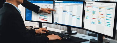 Projeyi koordine eden ve güncelleyen proje ekibi Gantt çizelge yazılımını kullanarak bilgisayarda program planladılar. Şirket işi için zaman ve süre belirleyen iş adamları. Önde.