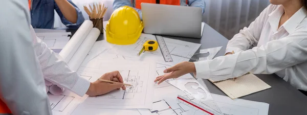 Engineer partner drawing and working on blueprint design together on office table for architectural building construction project. Architect drafting interior blueprint layout. Insight