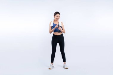 Atletik ve sportif Asyalı kadın yoğun kardiyo antrenmanından sonra dinleniyor ve su içiyor. Stüdyoda sağlıklı egzersiz ve vücut bakımına uygun yaşam tarzı takibi izole edilmiş bir arka plan. Kuvvetli