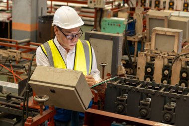 Fabrika mühendisi endüstriyel çelik oluşum makinesini teftiş ediyor. Metal makine mühendisliği denetim denetçisi olarak liderliği gösteriyor..
