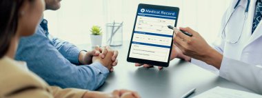 Doktor, doktor muayenehanesindeki genç çifte tablet ve şefkatli sağlık hizmetleri konsültasyonu hakkında tıbbi teşhis raporu göster. Tıbbi atama ve sağlık hizmeti konsepti. Neoterik