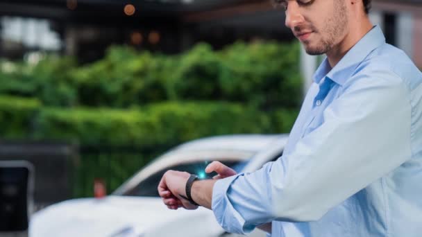 Empresário Verificar Estado Bateria Carro Holograma Smartwatch Enquanto Recarrega Partir — Vídeo de Stock