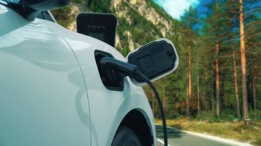 Elektrikli araç konsepti, yeşil çevre için yenilenebilir ve temiz enerjiyle çalışan EV otomobilinin varış noktasına ulaşmadan önce ormandaki şarj istasyonunun enerjisini şarj etmek için durur..
