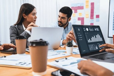 Çok ırklı analist ekibi toplantı masasındaki finansal verileri analiz etmek için BI Fintech yazılımı kullanıyor. Finansal konsol veri ekranında pazarlama göstergesi için analiz edilmiş grafikle birlikte. Uyum