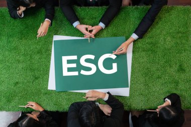 Çevre dostu sosyal yönetim kavramı olarak pazarlamayı planlayan çeşitli iş adamlarıyla yeşil çimen toplantı masasında panoramik afiş ESG sembolü. İlginç