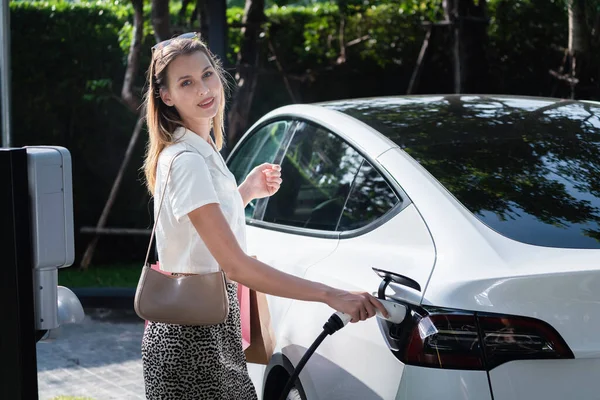Junge Frau Fährt Sommer Mit Elektroauto Ladung Grünen Nachhaltigen Stadtgarten — Stockfoto