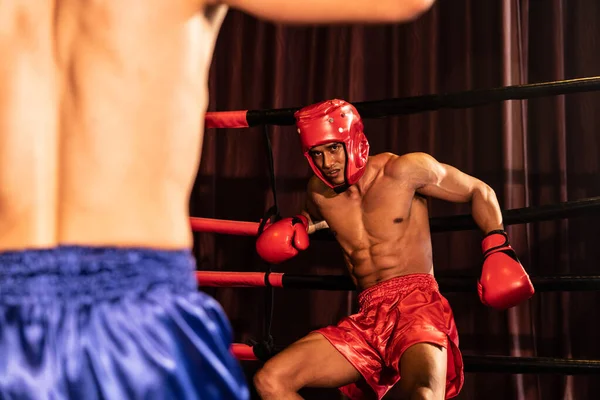拳击手带着拳击头盔在激烈和激烈的战斗中 而对手挣扎着背对着拳击台 表现出韧性和决心 Impetus — 图库照片